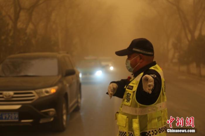 3月15日，甘肃多地遭遇沙尘天气，一名交警戴口罩执勤。 胡广信 摄
