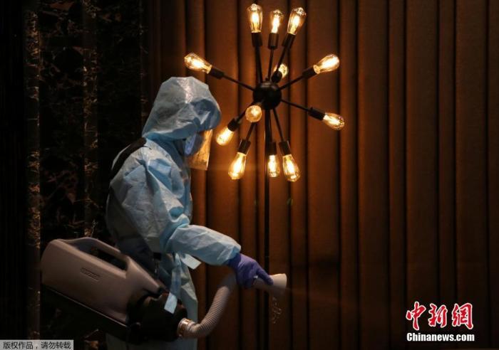 资料图：印度孟买，一名穿着个人防护设备的工人在电影院重新开放前为座椅消毒。